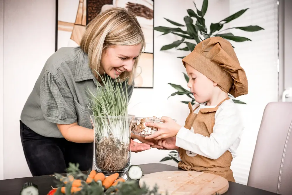 Anna kocht mit ihrem Sohn, der eine Papier-Kochmütze trägt