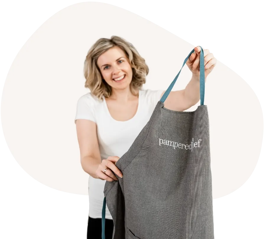 Anna hält lächelnd eine Pampered Chef Schürze hoch