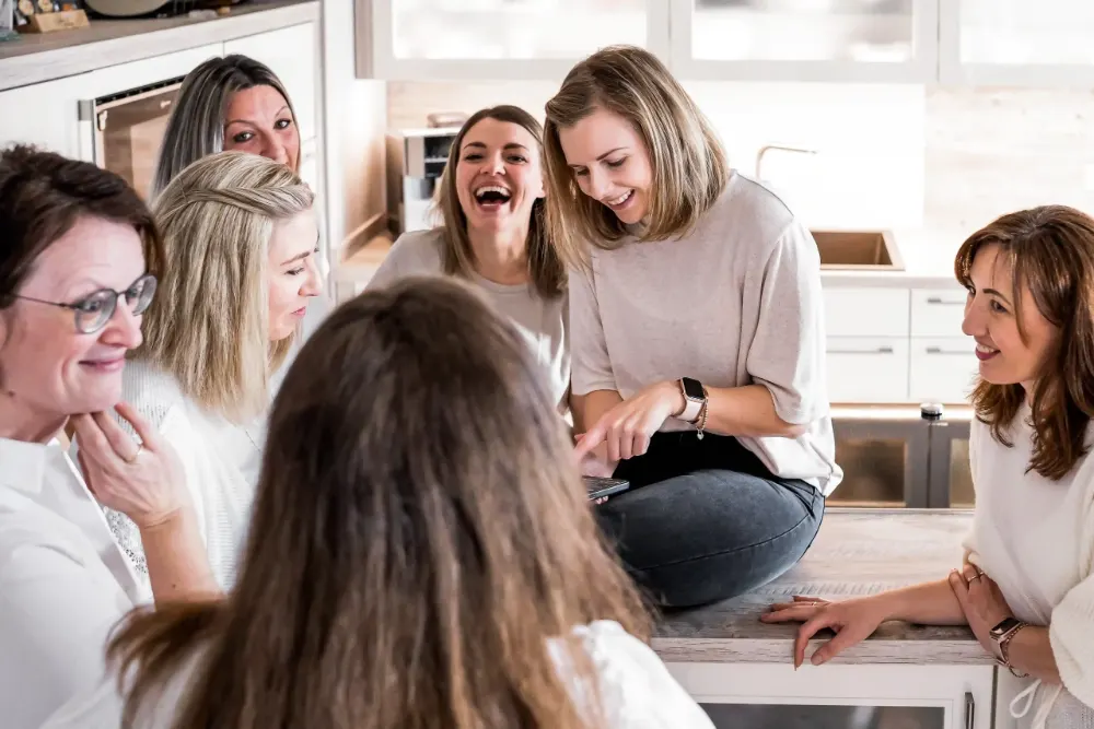Fünf Frauen aus der Crew lachen zusammen in einer Küche