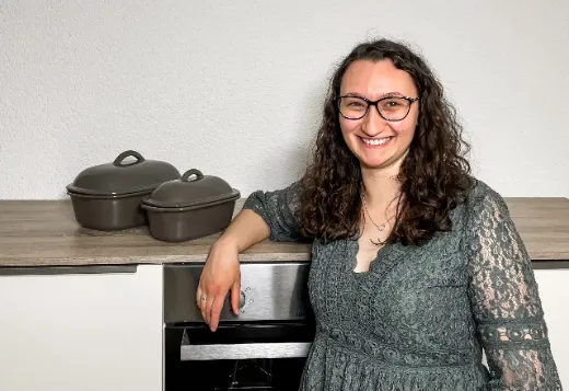 Emily lehnt lächelnd an ihrer Küchenzeile, daneben Ofenmeister und Ofenhexe