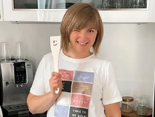 Irina lächelt in ihrer Küche und hält einen Pampered Chef Kochlöffel hoch