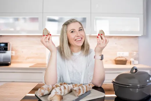 Katja hält lachend zwei frisch gebackene Brötchen hoch